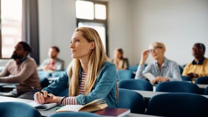 Erwachsene sitzen in einem Seminarraum und hören zu